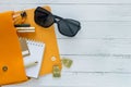 Fashion concept. Female things, cosmetic products, sunglass, notebook and orange handbag on wooden background with copyspace. Flat Royalty Free Stock Photo