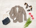 Fashion concept. Gray jacket, handbag, sunglasses, shoes and pink tulips. Top view, light wood background Royalty Free Stock Photo