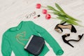 Fashion concept. Green blouse, handbag, sunglasses, black shoes and pink tulips. Top view, light wood background Royalty Free Stock Photo