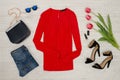 Fashion concept. Red blouse, jeans, handbag, sunglasses, black shoes, lipstick and pink tulips. Top view, light wood background Royalty Free Stock Photo