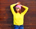 Fashion cool girl in colorful clothes over wooden background