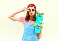 Fashion cool girl is pulling her lips with skateboard over white