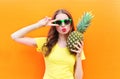 Fashion cool girl in sunglasses with pineapple over colorful orange Royalty Free Stock Photo