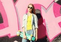 Fashion cool girl wearing a sunglasses, jeans shirt and skateboard