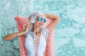 Girl with white hair in headphones listening to music on pink pool float