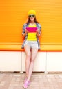 Fashion cool smiling girl using tablet pc over colorful orange