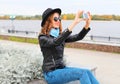 Fashion cool young smiling girl taking picture self portrait on smartphone in city Royalty Free Stock Photo