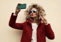 Fashion cool young woman blowing red lips taking selfie picture by smartphone showing peace hand sign wearing red jacket Royalty Free Stock Photo