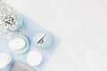 Fashion cosmetic products set on pastel blue color paper - white soap, towel, flowers, soap dispenser, blue ceramic vase, silver