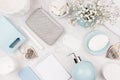 Fashion cosmetic products set - white soap, towel, flowers, soap dispenser, blue ceramic vase, silver cosmetic bag on white wood. Royalty Free Stock Photo