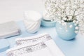 Fashion cosmetic products - white soap, towel, flowers, soap dispenser, blue ceramic vase, silver cosmetic bag on white wood.