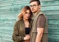 Fashion couple standing posing near green wooden wall Royalty Free Stock Photo
