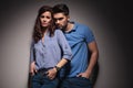 Fashion couple leaning embraced on a grey wall