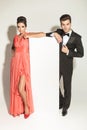Fashion couple leaning on a white empy board