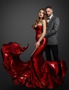 Fashion Couple in Love. Handsome Man embracing Sexy Woman in Red Dress with flying Fabric. Elegant Gentle in Suit and Model Royalty Free Stock Photo