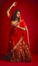 Fashion, dancing and Indian woman in a traditional dress, celebration and confident on a red studio background. Female