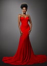 Fashion Dark Skin Woman in Red Sexy Dress. African Model with Afro Hairstyle in Long Evening Gown over Gray. Stylish Lady with Royalty Free Stock Photo