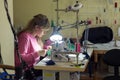 Fashion designer clothes sews on sewing machine by light lamp in workshop