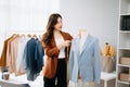 Fashion designer woman talking smart phone and using laptop with digital tablet computer in modern studio the clothes hanging on Royalty Free Stock Photo