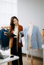 Fashion designer woman talking smart phone and using laptop with digital tablet computer in modern studio the clothes hanging on Royalty Free Stock Photo