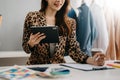 Fashion designer woman talking smart phone and using laptop with digital tablet computer in modern studio Royalty Free Stock Photo