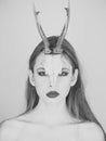 Fashion devil of mystic shaman girl with horns. Woman with makeup and antlers. Beauty look and cosmetics for skincare