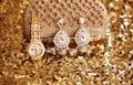 Fashion diamond earrings and golden wristwatch, womens accessories precious Gem Jewel Set on sequins sparkling sequined textile.
