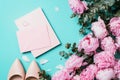 Fashion feminine blogger concept. Feminine workspace with notebook, shoes, pink peony, eucalyptus flower on blue background. Top