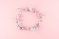 Fashion festive background with blank wreath of silver eucalyptus branches on pastel pink backdrop, top view, copy space.