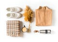 Fashion flat lay knolling with autumn and winter clothes - beige cozy sweater, plaid scarf sneakers, coffee and accessories on