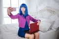 Fashion freak. Glamour emotionless synthetic girl, fake doll with blue hair is holding computer and doing selfie while