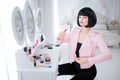 Fashion freak. Glamour synthetic girl, fake doll with empty look and short black hair is holding lipstick while sitting