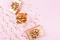 Fashion gift or present boxes with golden bows, serpentine and star confetti on pink pastel table top view. Christmas flat lay. Royalty Free Stock Photo