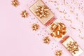 Fashion gift or present boxes with golden bows, serpentine and star confetti on pink pastel table top view. Christmas flat lay.