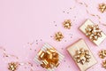 Fashion gifts or presents boxes with golden bows and star confetti on pink pastel background top view. Flat lay for Christmas