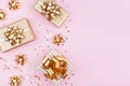 Fashion gifts or presents boxes with golden bows and star confetti on pink table top view. Flat lay for birthday or Christmas. Royalty Free Stock Photo