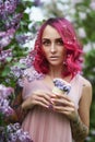 Fashion girl with bright red dyed hair in Apple and lilac flowers. Creative color bright pink, colorist. Woman walks in a Park Royalty Free Stock Photo