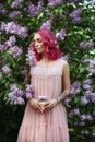 Fashion girl with bright red dyed hair in Apple and lilac flowers. Creative color bright pink, colorist. Woman walks in a Park Royalty Free Stock Photo