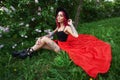 Fashion girl with bright red dyed hair in Apple and lilac flowers. Creative color bright pink, colorist. Woman walks in a Park Royalty Free Stock Photo