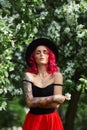 Fashion girl with bright red dyed hair in Apple and lilac flowers. Creative color bright pink, colorist. Woman walks in a Park Royalty Free Stock Photo