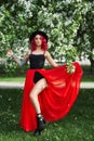 Fashion girl with bright red dyed hair in Apple and lilac flowers. Creative color bright pink, colorist. Woman walks in a Park Royalty Free Stock Photo