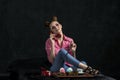 Fashion girl holds retro phone and drinks coffee with cakes. Style of the 80-90s. Young woman calling by phone while sitting on Royalty Free Stock Photo