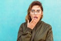 fashion girl in round glasses stands posing near a turquoise wall