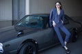 Fashion girl standing next to a retro sport car on the sun. Stylish woman in a gray suit waiting near classic car