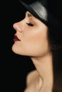 Fashion portrait in profile of a young sexy girl in a black hat with red lipstick Royalty Free Stock Photo