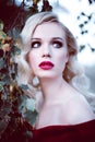 Fashion gorgeous young blonde woman in beautiful red dress in a fairy-tale forest. magic atmosphere. Retouched toning shot Royalty Free Stock Photo