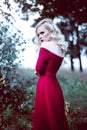 Fashion gorgeous young blonde woman in beautiful red dress in a fairy-tale forest. magic atmosphere. Retouched toning shot Royalty Free Stock Photo