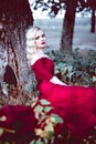 Fashion gorgeous young blonde woman in beautiful red dress in a fairy-tale forest. magic atmosphere. Retouched toning shot Royalty Free Stock Photo