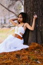 Fashion gorgeous young woman in beautiful white dress sitting on the ground in a fairy-tale forest Royalty Free Stock Photo