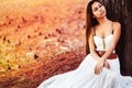 Fashion gorgeous young woman in beautiful white dress sitting on the ground in a fairy-tale forest Royalty Free Stock Photo